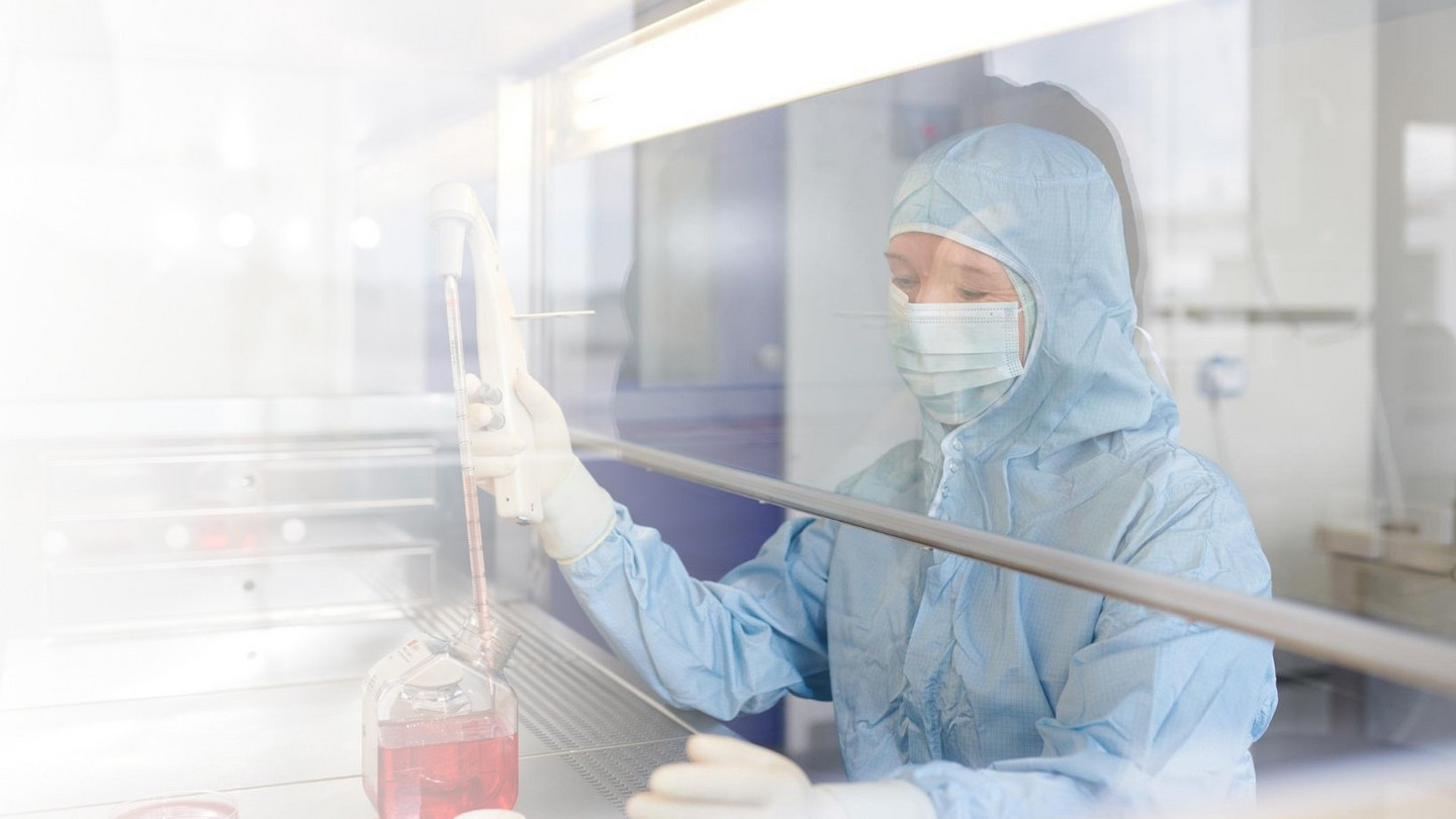 Mitarbeiterin der Transfusionsmedizin nimmt unter dem Abzug eine Flüssigkeit per Pipette auf.